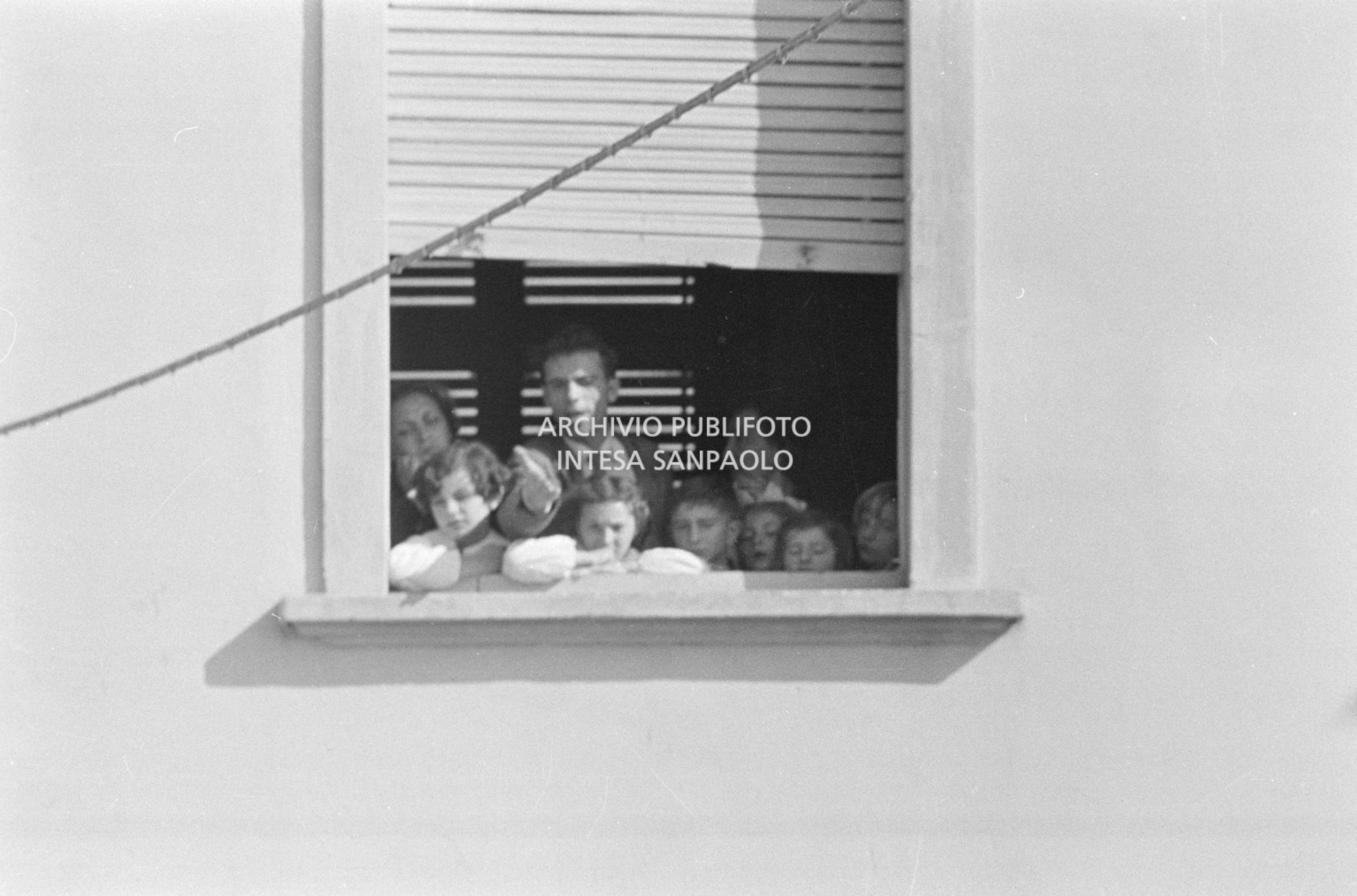 Alcuni alunni e due maestre, a una finestra della scuola elementare di Terrazzano, frazione di Rho in provincia di Milano, a fianco ad Arturo Santato, che, insieme al fratello Egidio, tiene in ostaggio gli alunni e le maestre