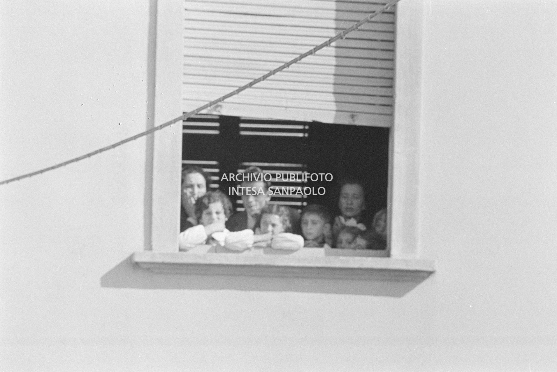 Alcuni alunni e due maestre, a una finestra della scuola elementare di Terrazzano, frazione di Rho in provincia di Milano, a fianco ad Arturo Santato, che, insieme al fratello Egidio, tiene in ostaggio gli alunni e le maestre