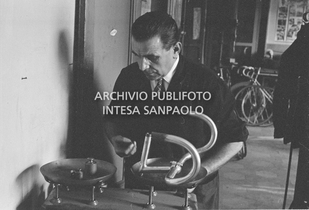 Il meccanico Giuseppe De Grandi, detto Pinella, pesa il manubrio di una bicicletta durante la preparazione di quella per Roger Rivière con la quale,  di lì a tre giorni, il ciclista francese si sarebbe aggiudicato il record dell'ora