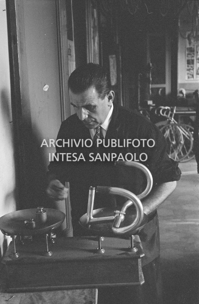 Il meccanico Giuseppe De Grandi, detto Pinella, pesa il manubrio di una bicicletta durante la preparazione di quella per Roger Rivière con la quale,  di lì a tre giorni, il ciclista francese si sarebbe aggiudicato il record dell'ora