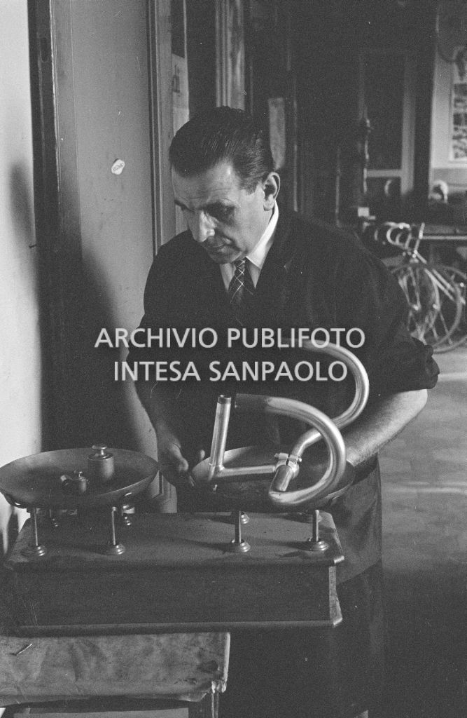 Il meccanico Giuseppe De Grandi, detto Pinella, pesa il manubrio di una bicicletta durante la preparazione di quella per Roger Rivière con la quale,  di lì a tre giorni, il ciclista francese si sarebbe aggiudicato il record dell'ora