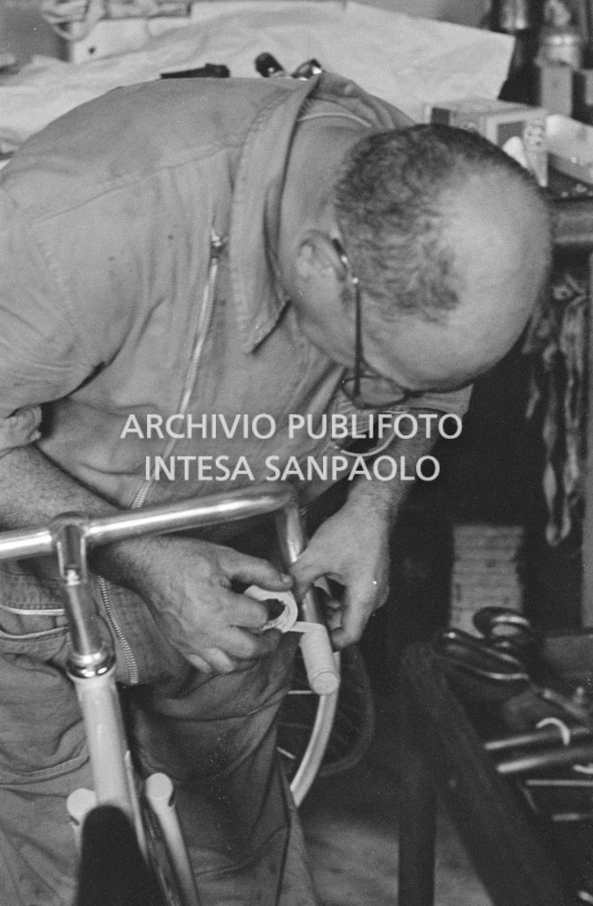L'assistente del meccanico Giuseppe De Grandi, detto Pinella, aiuta a preparare la bicicletta di Roger Rivière in vista del record dell'ora che il ciclista francese si sarebbe aggiudicato di lì a tre giorni