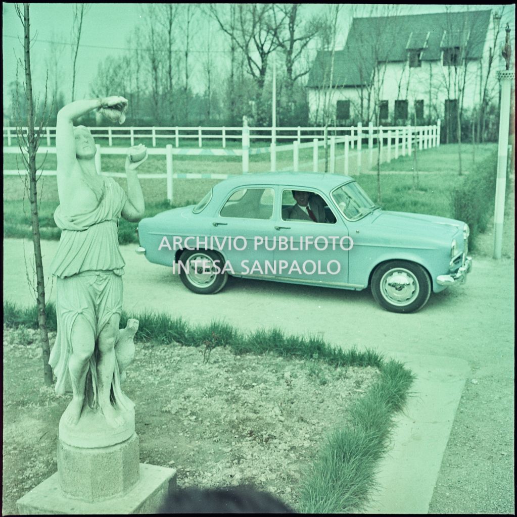 Alfa Romeo Giulietta berlina di colore azzurro in un giardino con a bordo un uomo