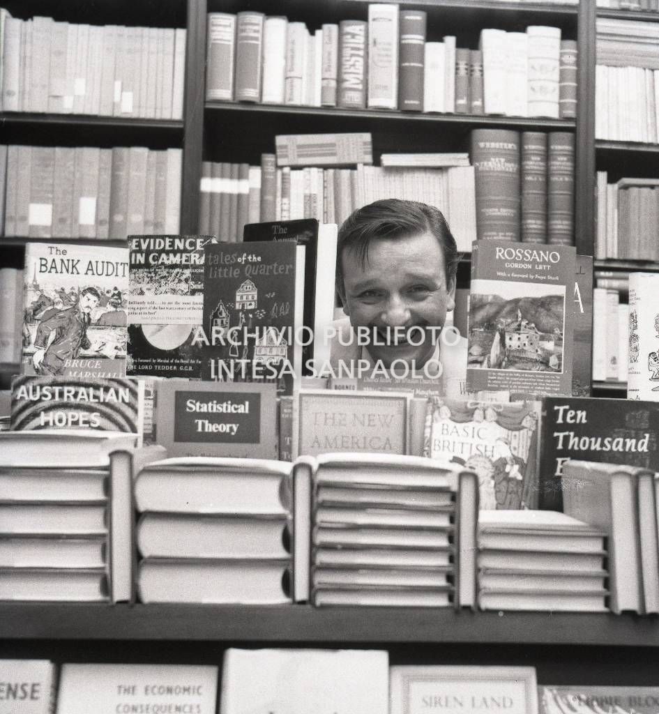 Fred Buscaglione in una libreria in posa tra i volumi su un banco