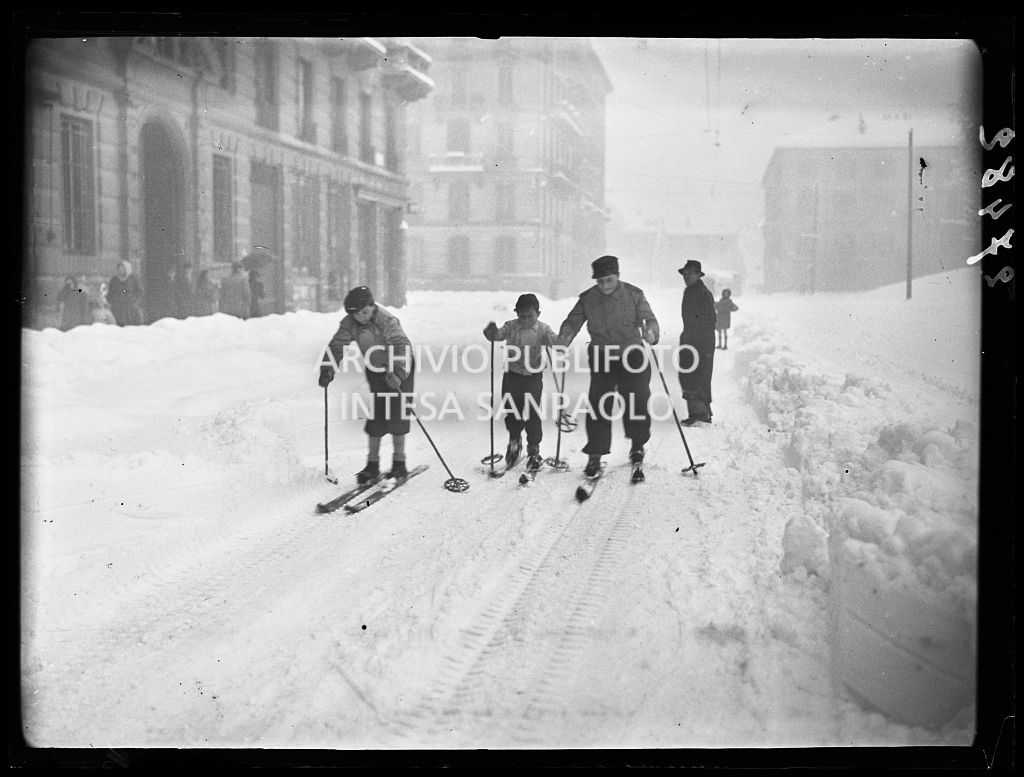 Milano coperta dalla neve: alcuni ragazzi sciano per le vie della città
