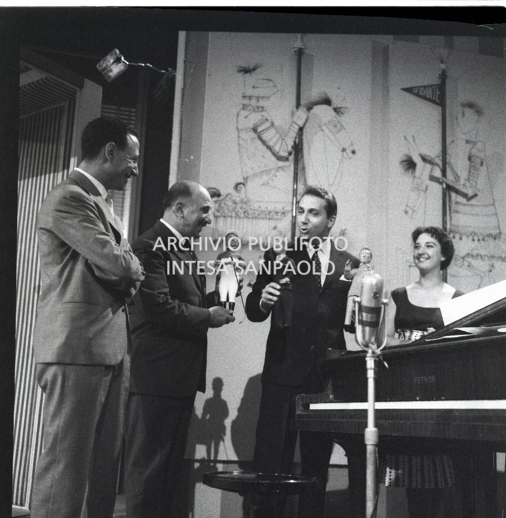 Mike Bongiorno conduce la trasmissione televisiva "Lascia o raddoppia?": l'ospite della serata è Renato Carosone qui ritratto con il conduttore, la signorina Fulvia Vedovelli e un altro partecipante