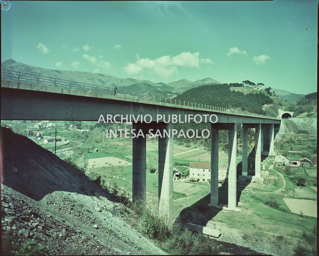 Viadotto in cemento che collega due montagne con valle abitata sottostante