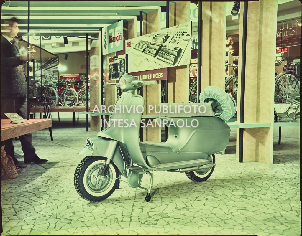 Moto scooter Bianchi  con ruota di scorta in esposizione allo stand della Fiera Campionaria di Milano del 1960