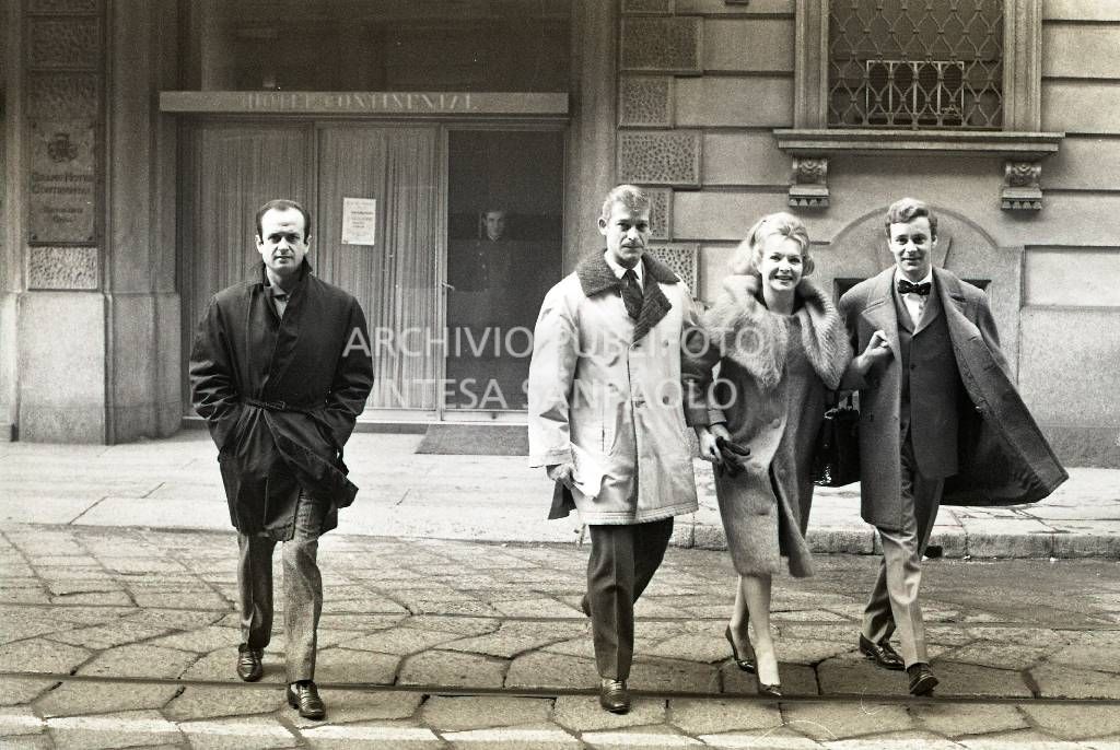 Line Renaud a braccetto con Paolo Poli (a destra) attraversa una via di Milano: sullo sfondo l'ingresso dell'Hotel Continental<br>709203/32