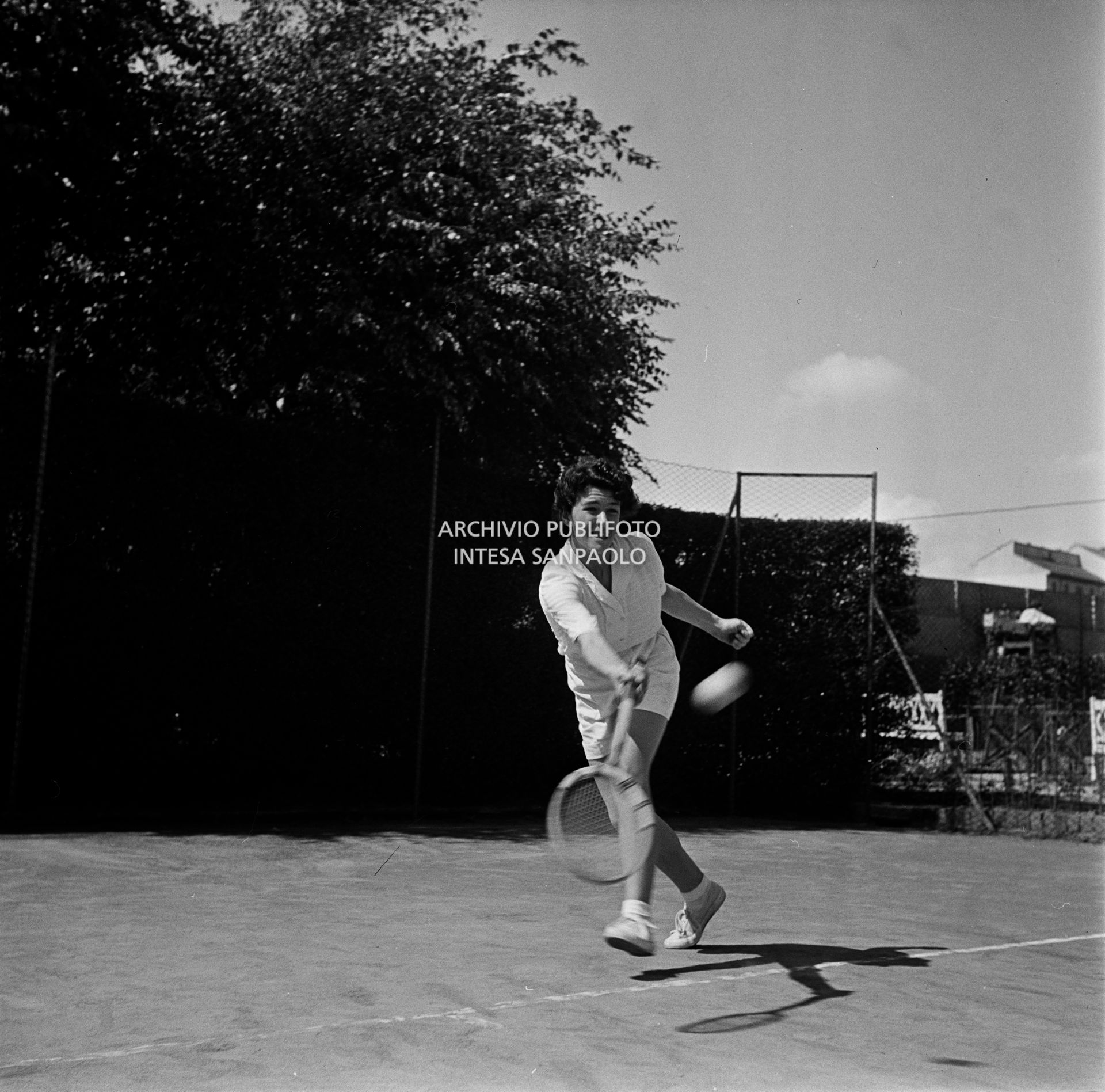 Una ragazza gioca a tennis in un campo all'aperto di Milano<br>73104