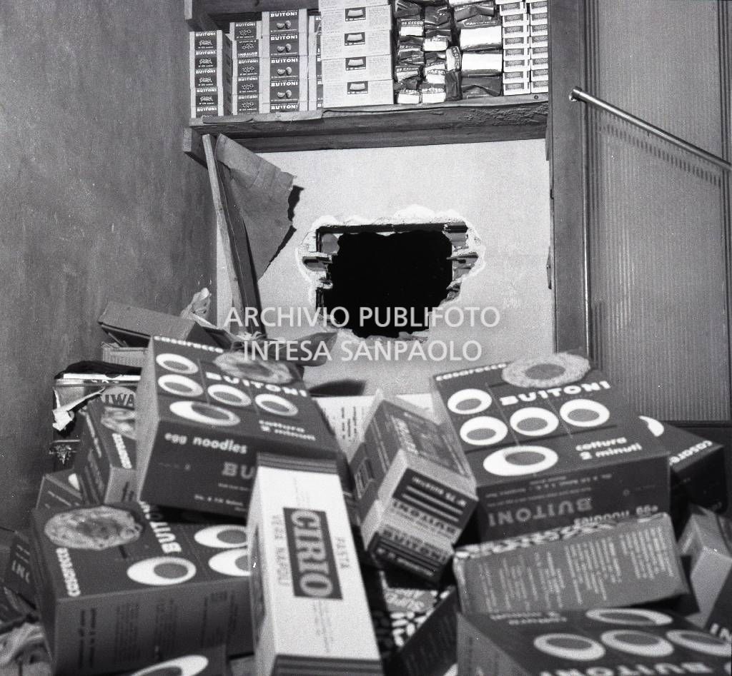 Il buco nel muro della panetteria, adiacente alla gioielleria, dal quale i rapinatori sono entrati nel negozio per poi introdursi nell'oreficeria; in primo piano varie scatole di prodotti alimentari messi a soqquadro<br>709121/1