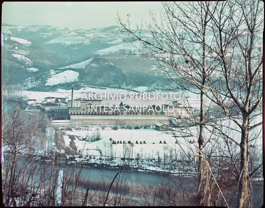 Veduta esterna del cotonificio Olcese circondato da un paesaggio montano innevato e dal fiume Oglio