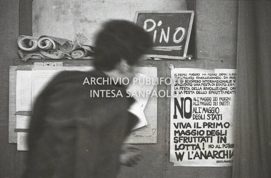 Un uomo di spalle al circolo anarchico Ponte della Ghisolfa; dietro di lui su una lavagnetta la scritta "Pino"<br>731758/1