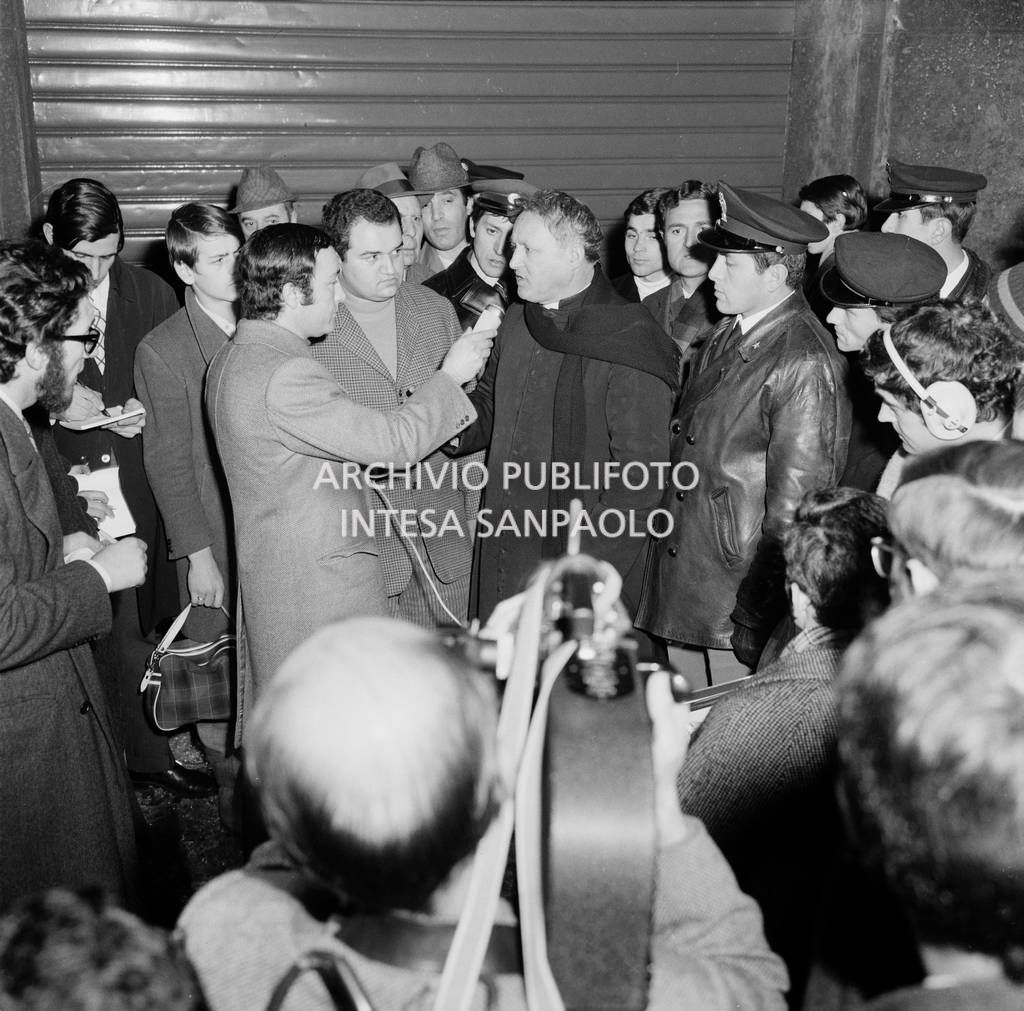 Un giornalista intervista Don Corrado Fioravanti, parroco di Cinisello Balsamo, che era presente al momento dello scoppio della bomba nei locali della Banca Nazionale dell'Agricoltura, in piazza Fontana a Milano