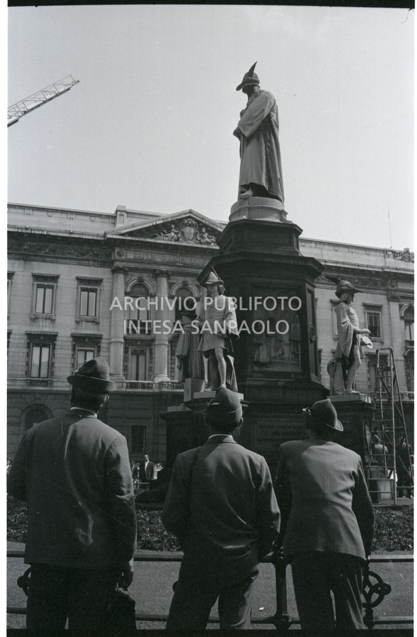 Tre alpini ammirano il monumento a Leonardo da Vinci, in piazza della Scala a Milano, decorato con i cappelli del Corpo<br>528538