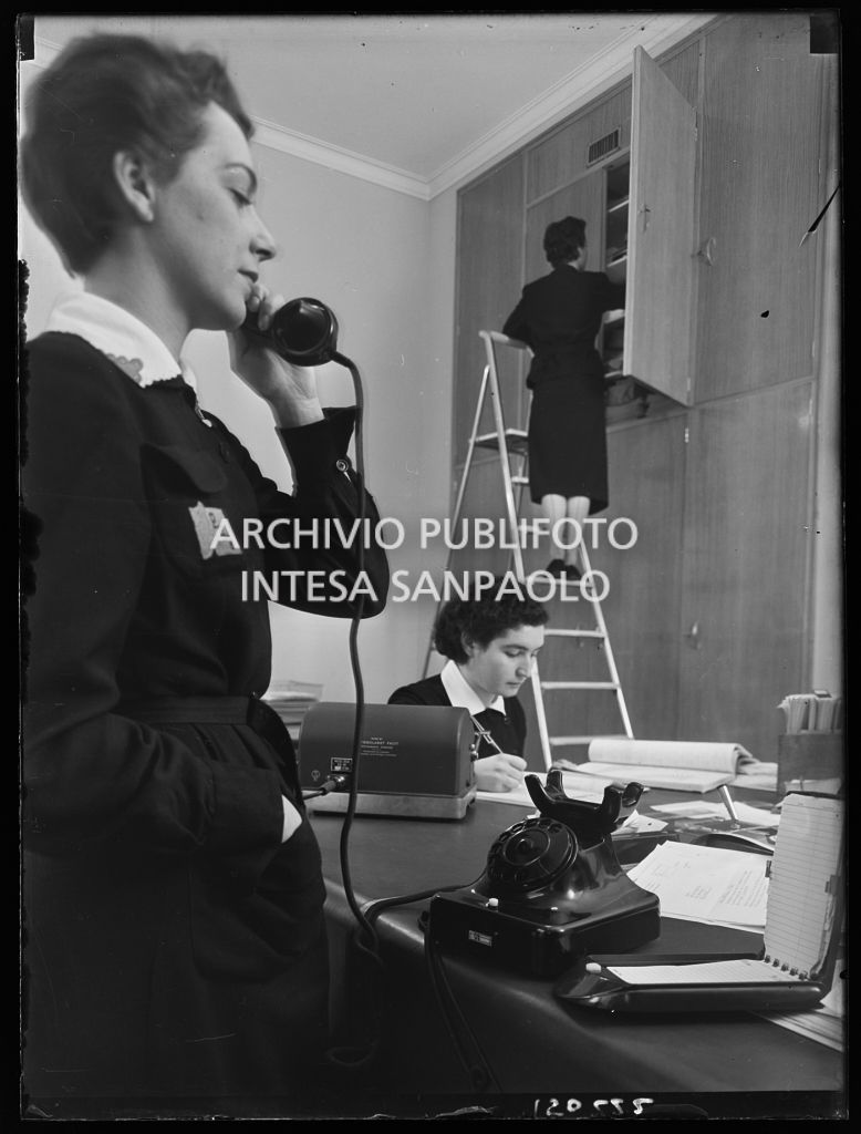 Impiegate al lavoro nei nuovi uffici della Omnia Pubblicità; in primo piano un'impiegata al telefono