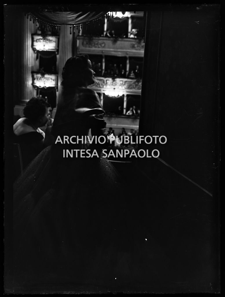 Due donne, in penombra, in un palco al Teatro alla Scala assistono all'opera "La Wally", di Alfredo Catalani, diretta da Carlo Maria Giulini, con la regia di Tatiana Pavlova, in occasione della serata inaugurale della stagione lirica 1953-1954