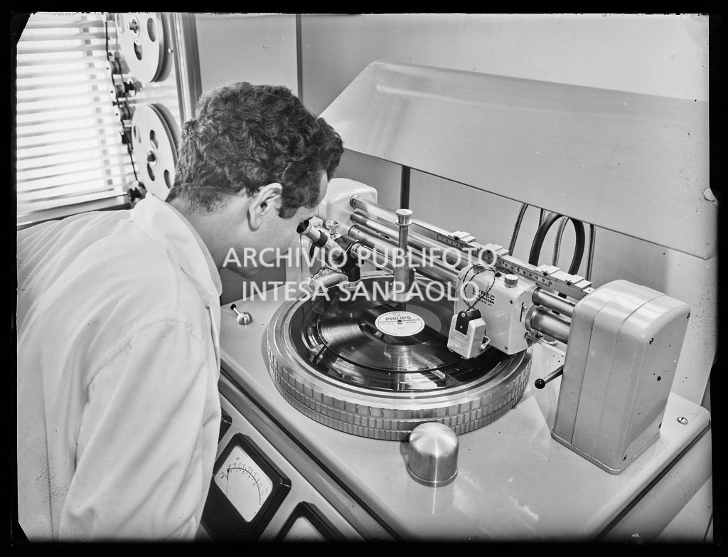 Un tecnico controlla al microscopio i microsolchi  di un disco in vinile appena prodotto