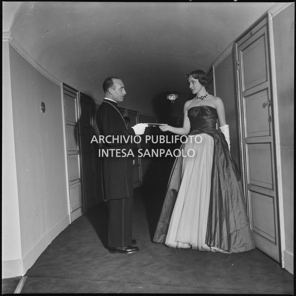 Una maschera del Teatro porge il libretto di sala a Emanuela di Castelbarco Toscanini in occasione della serata inaugurale della stagione lirica 1952-1953 con l'opera "Macbeth", di Giuseppe Verdi, diretta da Victor de Sabata, con la regia di Carl Ebert