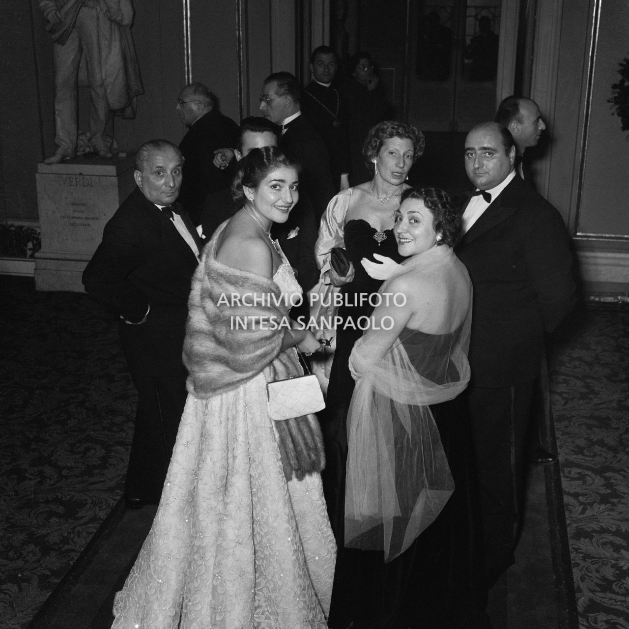La soprano Maria Callas insieme ad altri spettatori, nel foyer del Teatro alla Scala in occasione della serata inaugurale della stagione lirica 1953-1954 con l'opera "La Wally", di Alfredo Catalani, diretta da Carlo Maria Giulini, con la regia di Tatiana Pavlova