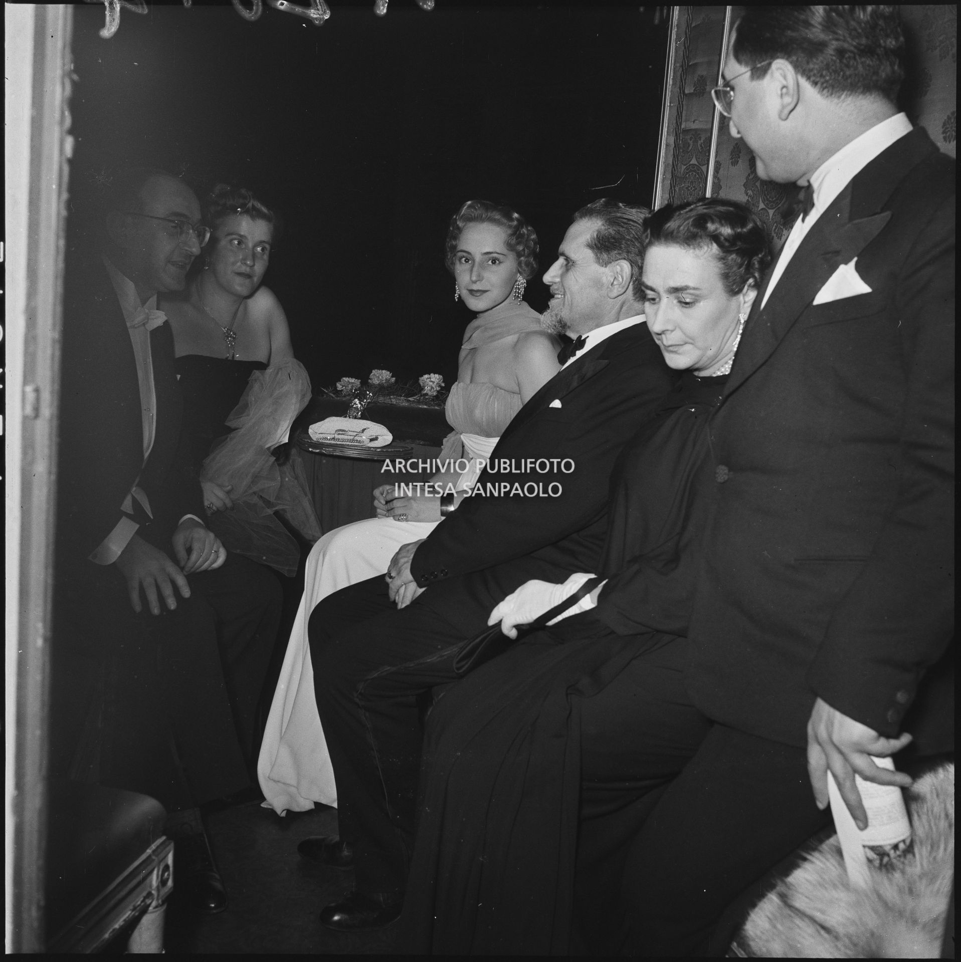Teodoro Bubbio, seduto tra Wally Toscanini e Emanuela di Castelbarco , con altri spettatori, in un palco del Teatro alla Scala in occasione della serata inaugurale della stagione lirica 1953-1954 con l'opera "La Wally", di Alfredo Catalani, diretta da Carlo Maria Giulini, con la regia di Tatiana Pavlova