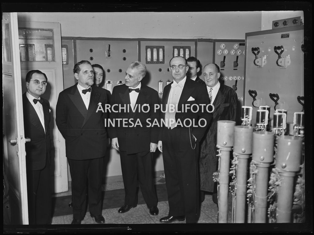 Il senatore Teodoro Bubbio (secondo da sinistra) accompagnato, tra gli altri, da Antonio Ghiringhelli, sovrintendente del Teatro alla Scala (terzo da sinistra), nei locali di controllo attrezzature di scena, dietro alla quinte, la sera dell'inaugurazione della stagione lirica 1953-1954 con l'opera "La Wally", di Alfredo Catalani, diretta da Carlo Maria Giulini, con la regia di Tatiana Pavlova