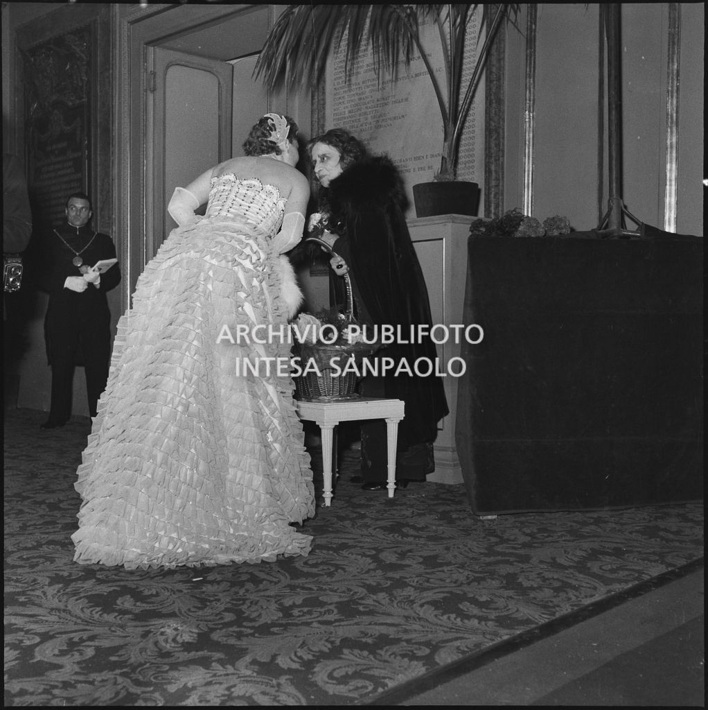 Cecilia Malvezzi Dondina con la fioraia nel foyer del Teatro alla Scala  in occasione della serata inaugurale della stagione lirica 1954-1955 con l'opera "La Vestale", di Gaspare Spontini, diretta da Antonino Votto, con la regia di Luchino Visconti