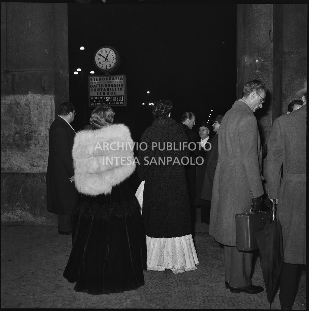 Spettatori usciti dal Teatro alla Scala dove hanno assistito alla serata inaugurale della stagione lirica 1954-1955 con l'opera "La Vestale", di Gaspare Spontini, diretta da Antonino Votto, con la regia di Luchino Visconti