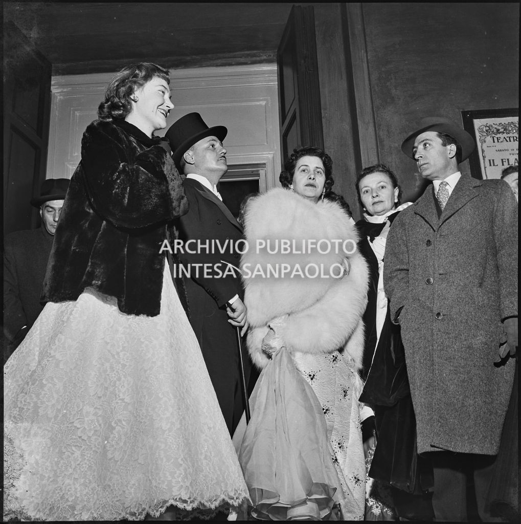 Lo stilista Pierre Balmain con altri spettatori nella galleria delle carrozze del Teatro alla Scala la sera dell'inaugurazione della stagione lirica 1955-1956 con l'opera "Norma" di Vincenzo Bellini, diretta da Antonino Votto con la regia di Margherita Wallmann