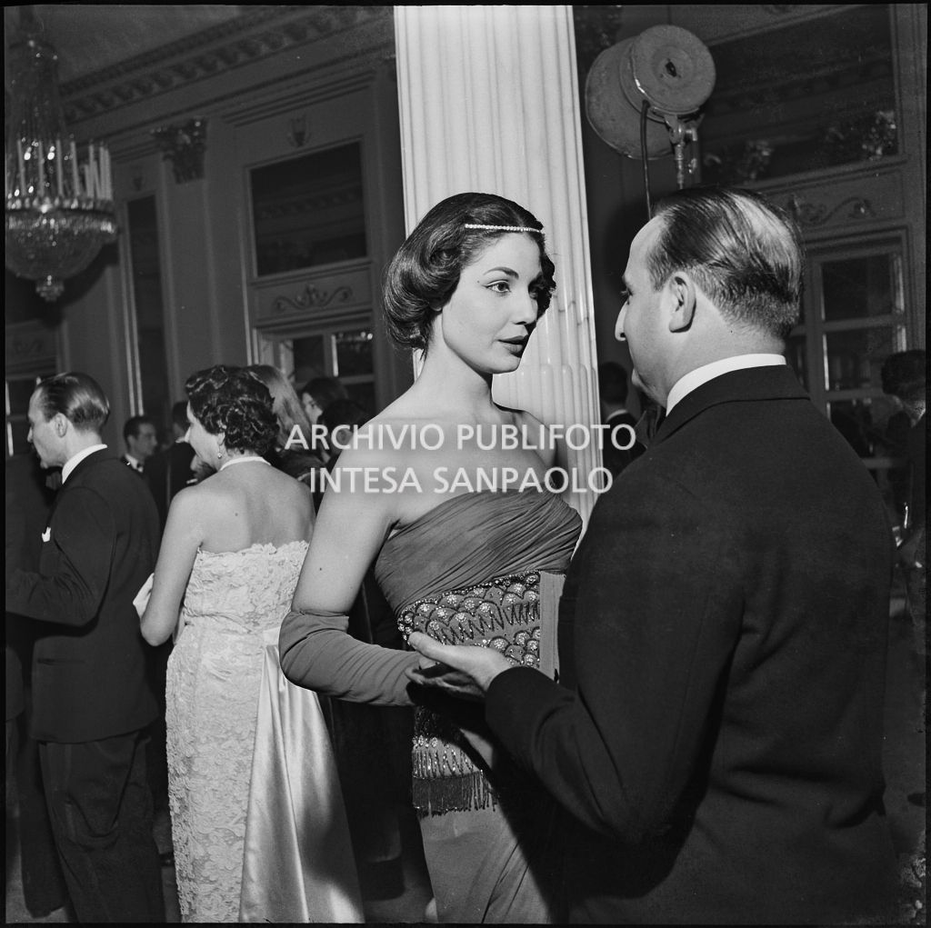 Eletta Polvani conversa con un uomo nel foyer del Teatro alla Scala in occasione della serata inaugurale della stagione lirica 1956-1957 con l'opera "Aida" di Giuseppe Verdi, diretta da Antonino Votto con la regia di Franco Enriquez