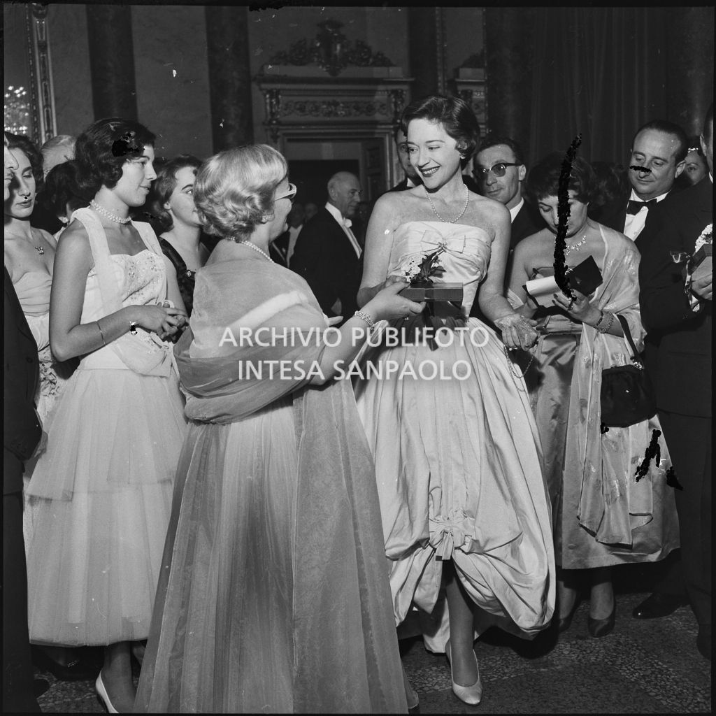 Jole Veneziani consegna un pacchetto alla contessa Anna Sogno al Teatro alla Scala in occasione della serata inaugurale della stagione lirica 1957-1958 con l'opera "Un ballo in maschera", di Giuseppe Verdi, diretta da Gianandrea Gavazzeni e la regia di Margherita Wallmann