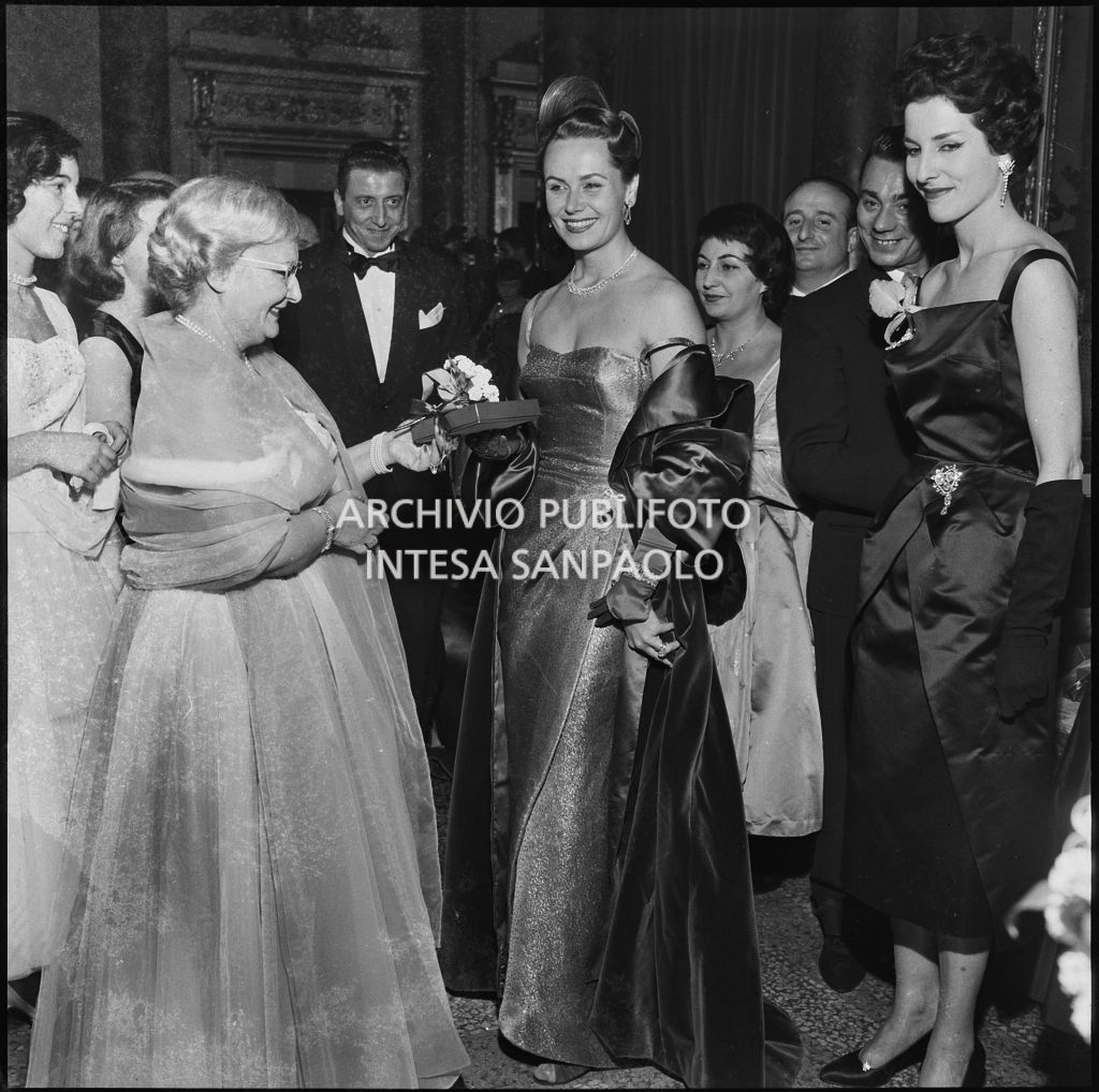 Jole Veneziani consegna un pacchetto alla signora De Bellis al Teatro alla Scala in occasione della serata inaugurale della stagione lirica 1957-1958 con l'opera "Un ballo in maschera", di Giuseppe Verdi, diretta da Gianandrea Gavazzeni e la regia di Margherita Wallmann