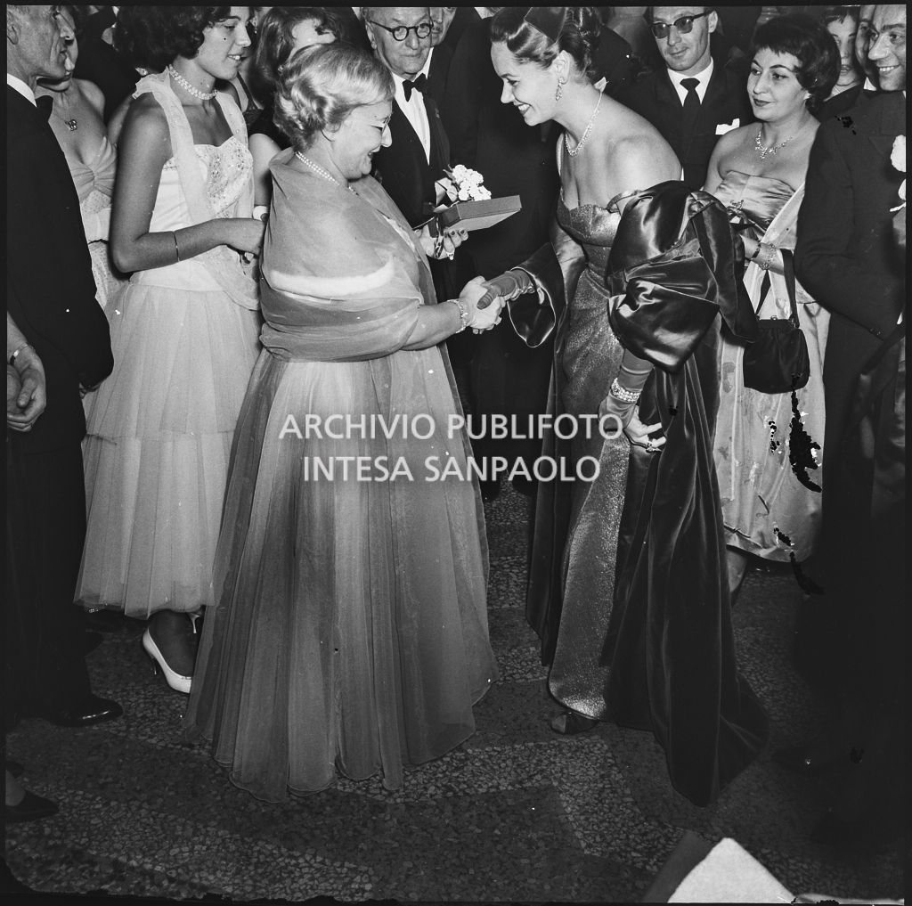 Jole Veneziani stringe la mano alla signora De Bellis al Teatro alla Scala in occasione della serata inaugurale della stagione lirica 1957-1958 con l'opera "Un ballo in maschera", di Giuseppe Verdi, diretta da Gianandrea Gavazzeni e la regia di Margherita Wallmann