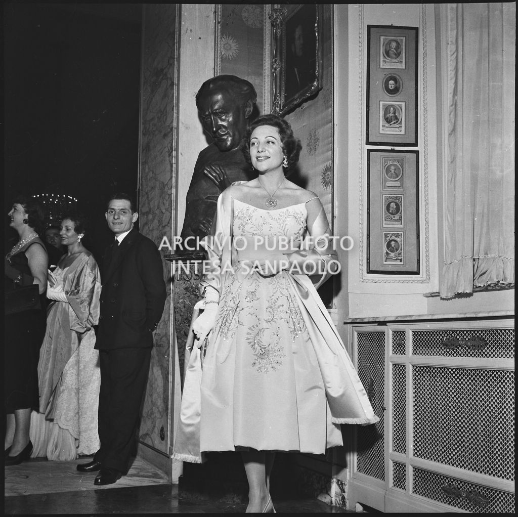 La ballerina Luciana Novaro in posa davanti al mezzobusto di Arturo Toscanini al museo de Teatro alla Scala in occasione della serata inaugurale della stagione lirica 1957-1958 con l'opera "Un ballo in maschera", di Giuseppe Verdi, diretta da Gianandrea Gavazzeni e la regia di Margherita Wallmann