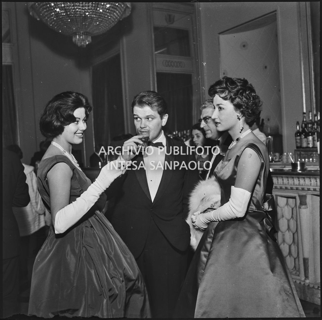 Giovanna Lomazzi in compagnia di due spettatori all bar del Teatro alla Scala in occasione della serata inaugurale della stagione lirica 1957-1958 con l'opera "Un ballo in maschera", di Giuseppe Verdi, diretta da Gianandrea Gavazzeni e la regia di Margherita Wallmann