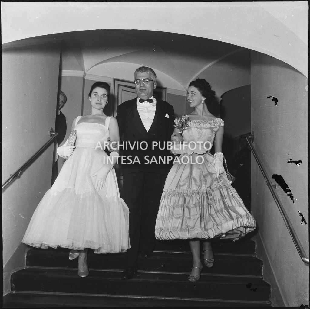 Antonia e Stellina Magri, nipoti del sovrintendente al Teatro alla Scala Antonio Ghiringhelli, in compagnia di uno spettatore al Teatro alla Scala in occasione della serata inaugurale della stagione lirica 1957-1958 con l'opera "Un ballo in maschera", di Giuseppe Verdi, diretta da Gianandrea Gavazzeni e la regia di Margherita Wallmann