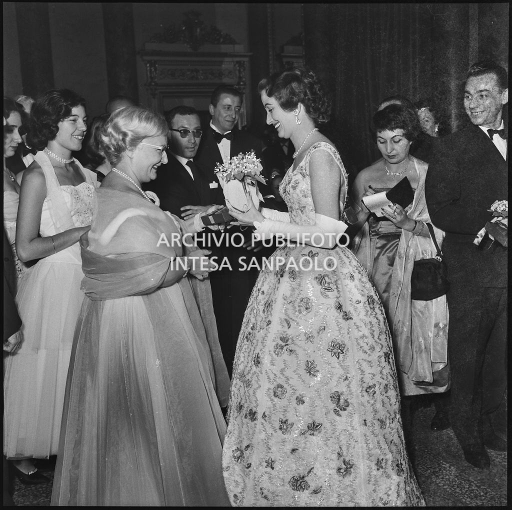 Jole Veneziani consegna un pacchetto a Grazia Bossi al Teatro alla Scala in occasione della serata inaugurale della stagione lirica 1957-1958 con l'opera "Un ballo in maschera", di Giuseppe Verdi, diretta da Gianandrea Gavazzeni e la regia di Margherita Wallmann