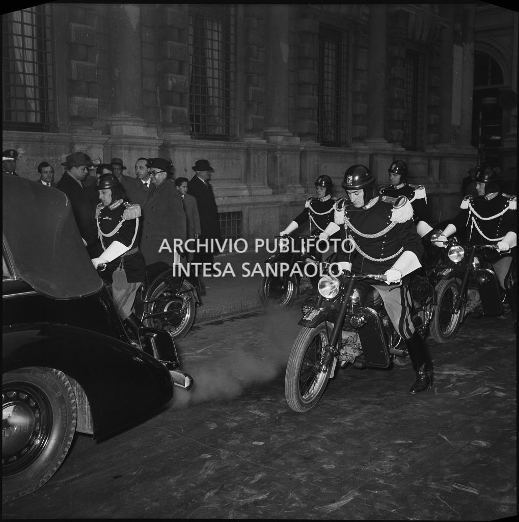 Corazzieri in motocicletta scortano l'automobile presidenziale, con a bordo Giovanni Gronchi, al Teatro alla Scala per assistere alla serata inaugurale della stagione lirica 1955-1956 con l'opera "Norma" di Vincenzo Bellini, diretta da Antonino Votto, con la regia di Margherita Wallmann