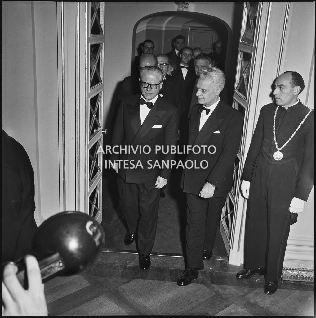 Il presidente della Repubblica Giovanni Gronchi al Teatro alla Scala accompagnato, tra gli altri, dal sovrintendente Antonio Ghringhelli in occasione della serata inaugurale della stagione lirica 1955-1956 con l'opera "Norma" di Vincenzo Bellini, diretta da Antonino Votto, con la regia di Margherita Wallmann