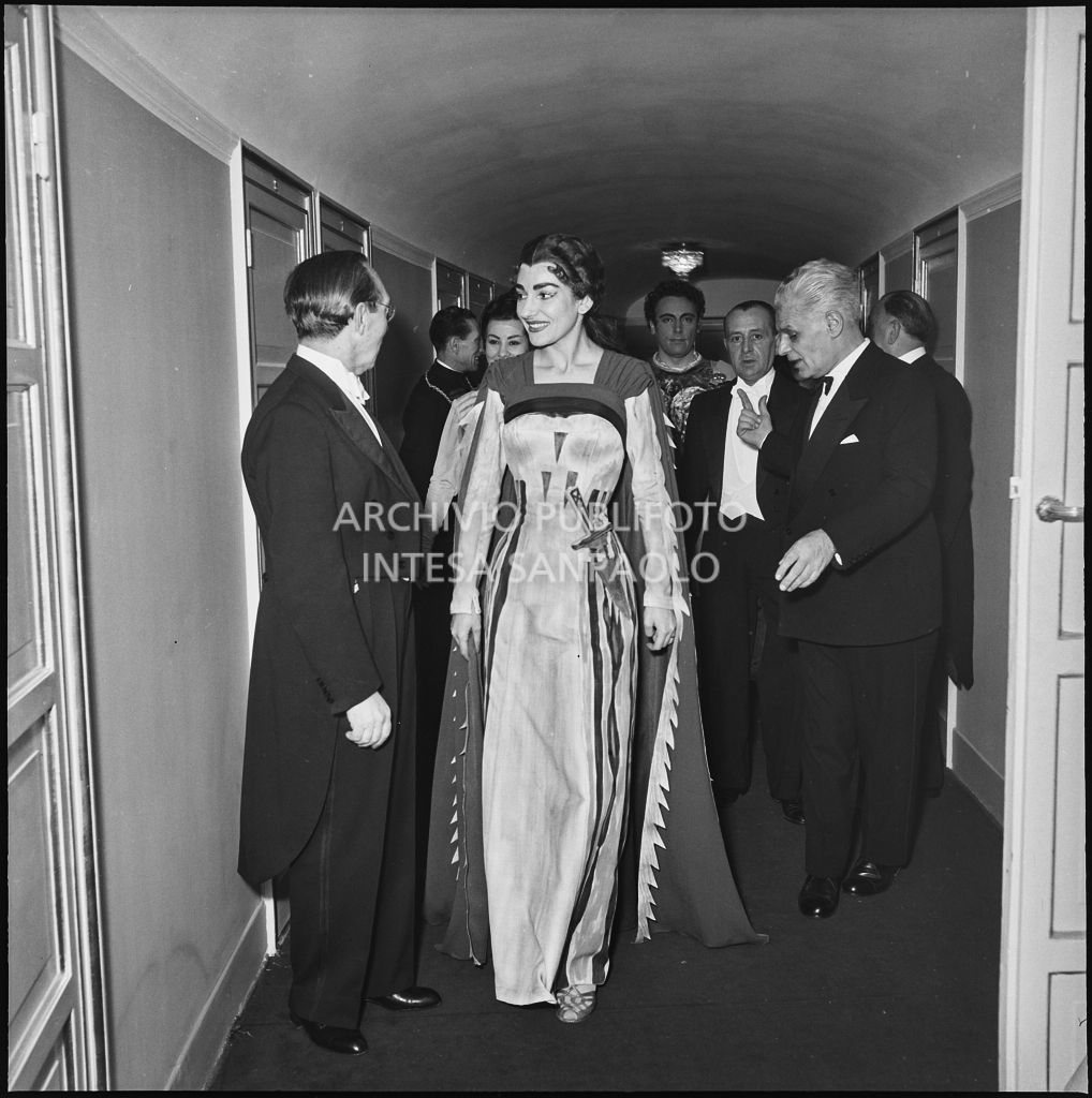 La soprano Maria Callas, in costume di scena, al Teatro alla  Scala con il direttore d'orchestra Antonino Votto e il soprintendente del Teatro Antonio Ghiringhelli in occasione della serata inaugurale della stagione lirica 1955-1956 con l'opera "Norma" di Vincenzo Bellini, diretta da Antonino Votto, con la regia di Margherita Wallmann