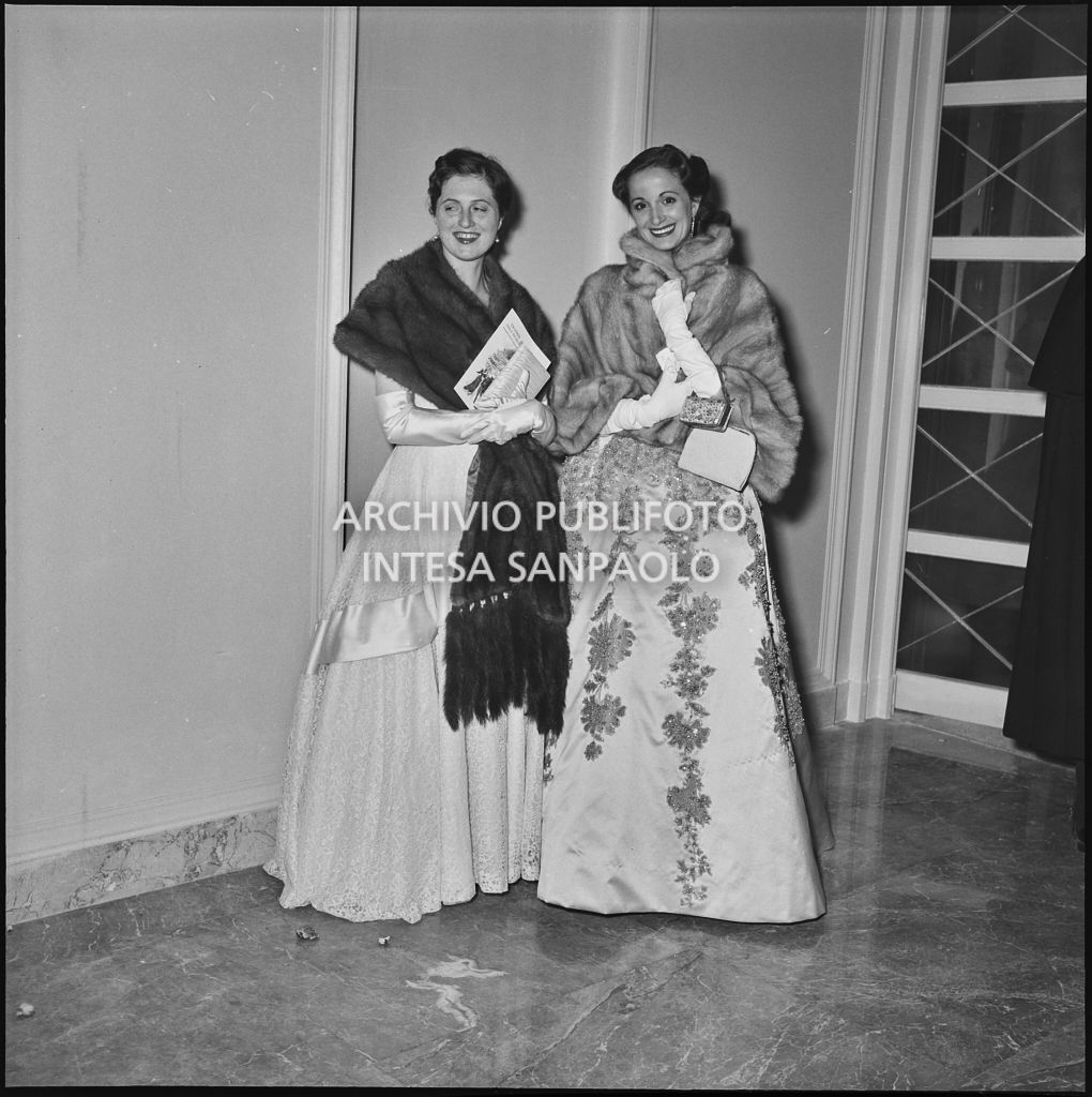 Due spettatrici, al Teatro alla  Scala, in occasione della serata inaugurale della stagione lirica 1955-1956 con l'opera "Norma" di Vincenzo Bellini, diretta da Antonino Votto, con la regia di Margherita Wallmann