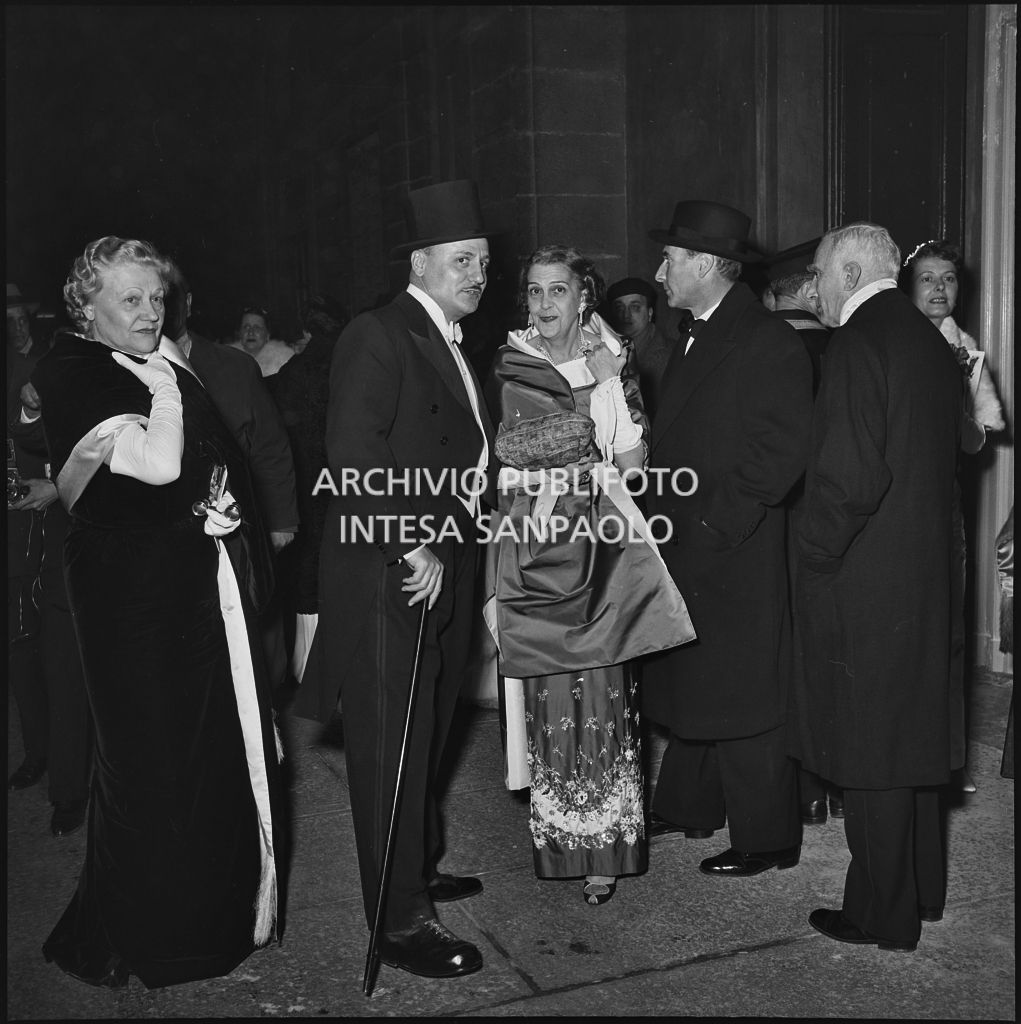 Spettatori all'esterno del Teatro alla Scala in occasione della serata inaugurale della stagione lirica 1955-1956 con l'opera "Norma" di Vincenzo Bellini, diretta da Antonino Votto, con la regia di Margherita Wallmann