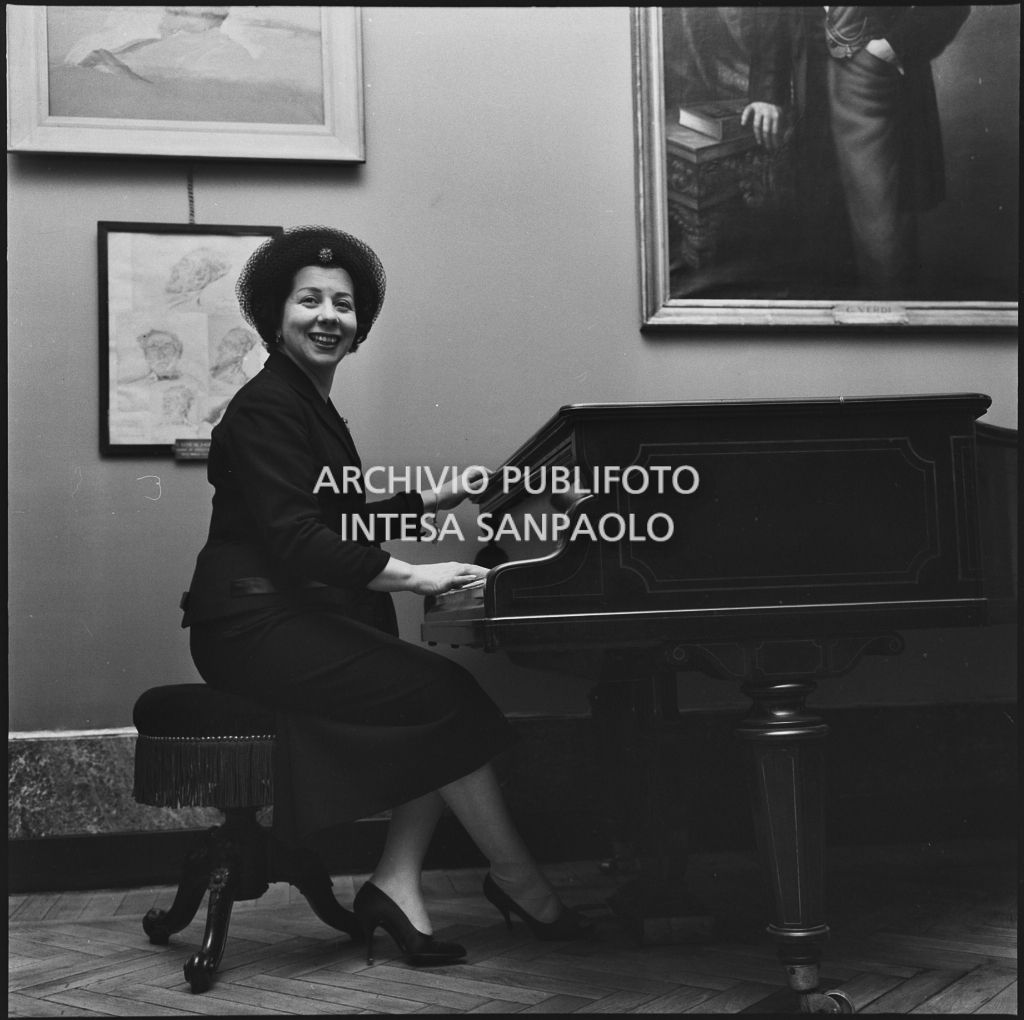 Il mezzosoprano Giulietta Simionato ritratta al pianoforte in occasione della serata inaugurale della stagione lirica 1957-1958  del Teatro alla Scala con l'opera di Giuseppe Verdi "Un ballo in maschera", diretta da Gianandrea Gavazzeni e con la regia di Margherita Wallmann