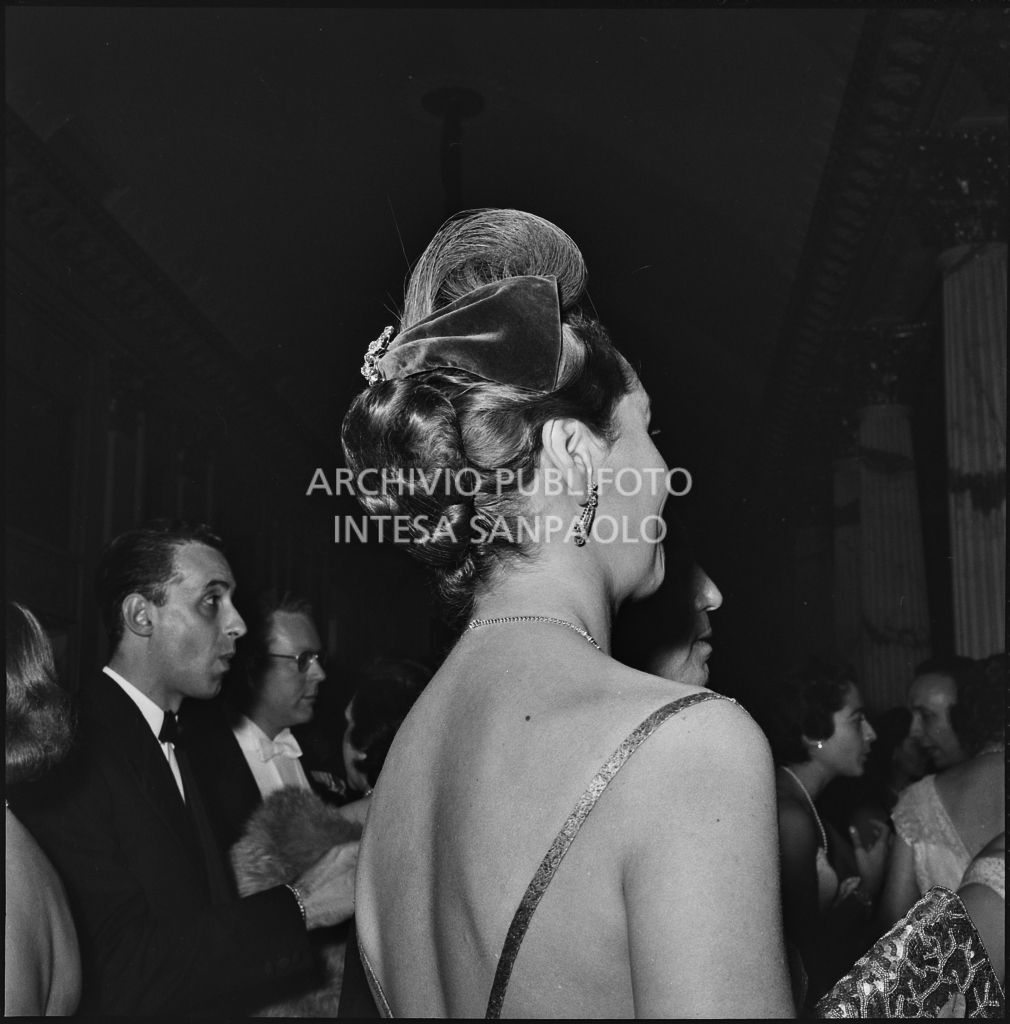 Acconciatura di una spettatrice nel foyer del Teatro alla Scala, in occasione della serata inaugurale della stagione lirica 1957-1958 con l'opera di Giuseppe Verdi "Un ballo in maschera", diretta da Gianandrea 
				Gavazzeni e con la regia di Margherita Wallmann