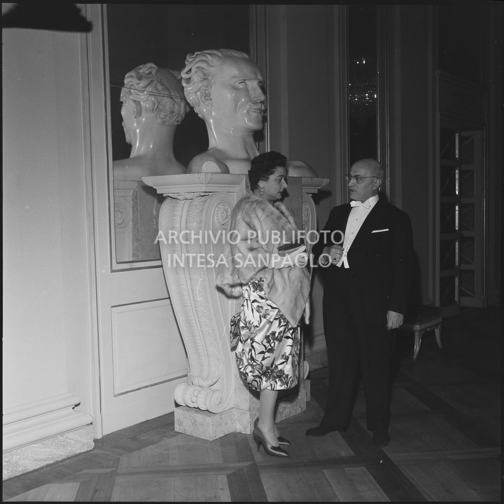 I signori Buzzi davanti al busto di Arturo Toscanini, al Teatro alla Scala, in occasione della serata inaugurale della stagione lirica 1958-1959 con l'opera "Turandot" di Giacomo Puccini, diretta da Antonino Votto con la regia di Margherita Walmann