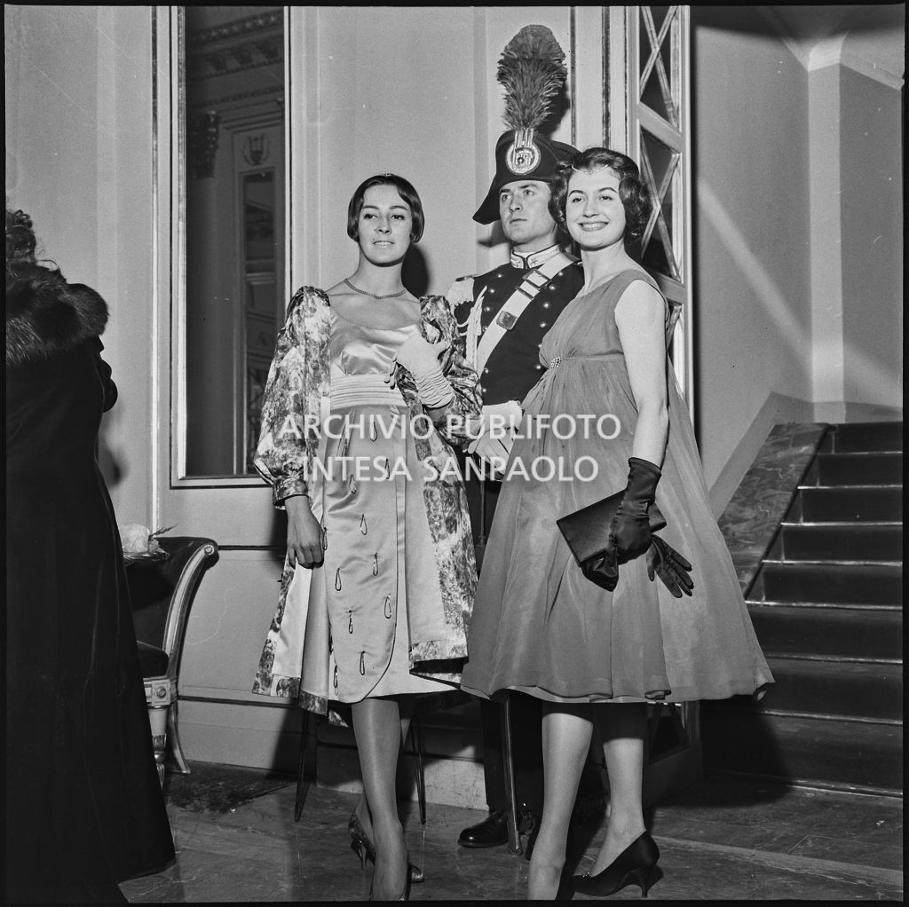Le ballerine Carmen Puthod e Carla Fracci in posa davanti a un carabiniere al Teatro alla Scala in occasione della serata inaugurale della stagione lirica 1958-1959 con l'opera "Turandot" di Giacomo Puccini, diretta da Antonino Votto con la regia di Margherita Walmann