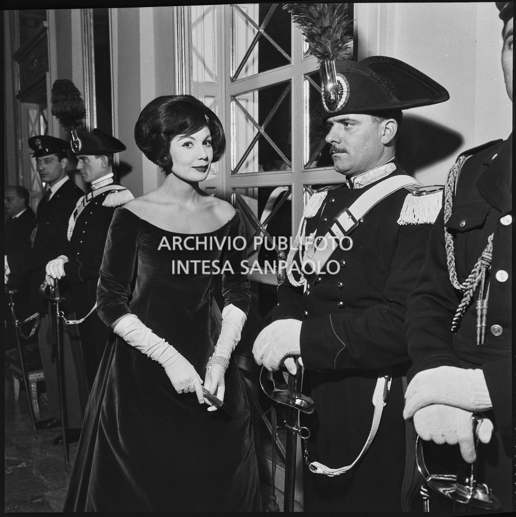Eletta Polvani a fianco ai carabinieri nel foyer del Teatro alla Scala in occasione della serata inaugurale della stagione lirica 1958-1959 con l'opera "Turandot" di Giacomo Puccini, diretta da Antonino Votto con la regia di Margherita Walmann