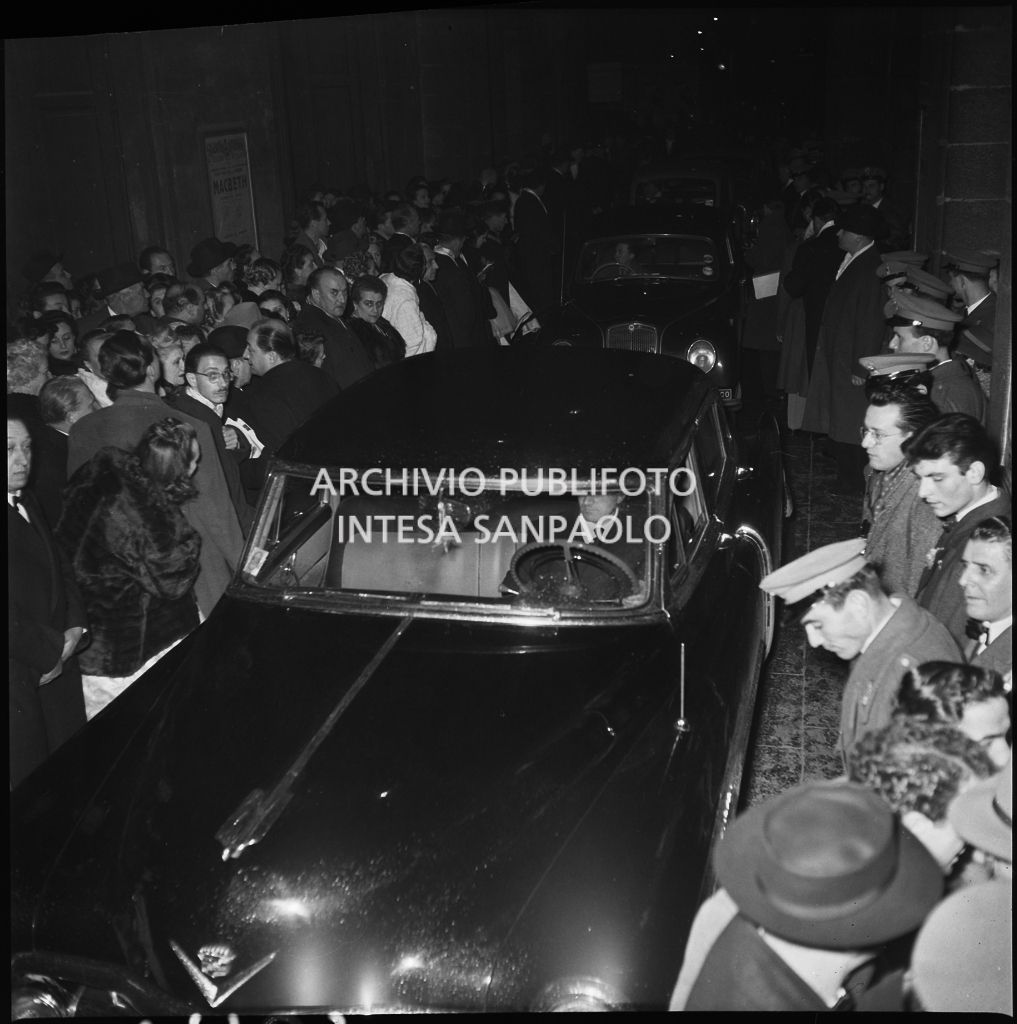 Un'automobile tra gli spettatori affollati all'esterno del Teatro alla Scala, nella galleria delle carrozze, la sera dell'inaugurazione della stagione lirica 1952-1953 con l'opera "Macbeth", di Giuseppe Verdi, diretta da Victor de Sabata, con la regia di Carl Ebert