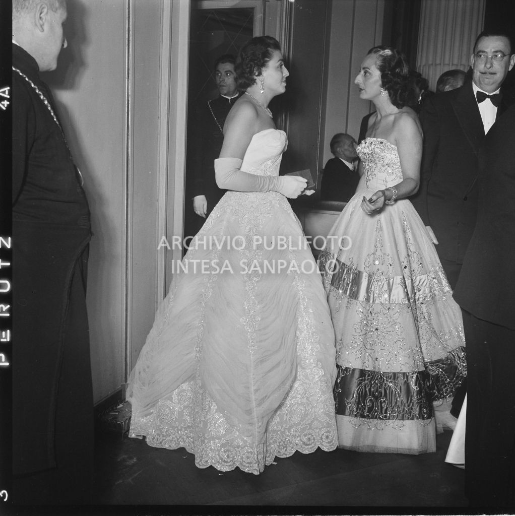 Rita Bernocchi Cerri e Lidia Bernocchi Bonetti nel foyer del Teatro alla Scala, in occasione della serata inaugurale della stagione lirica 1953-1954 con l'opera "La Wally", di Alfredo Catalani, diretta da Carlo Maria Giulini, con la regia di Tatiana Pavlova; alle sue spalle la locandina dell'opera