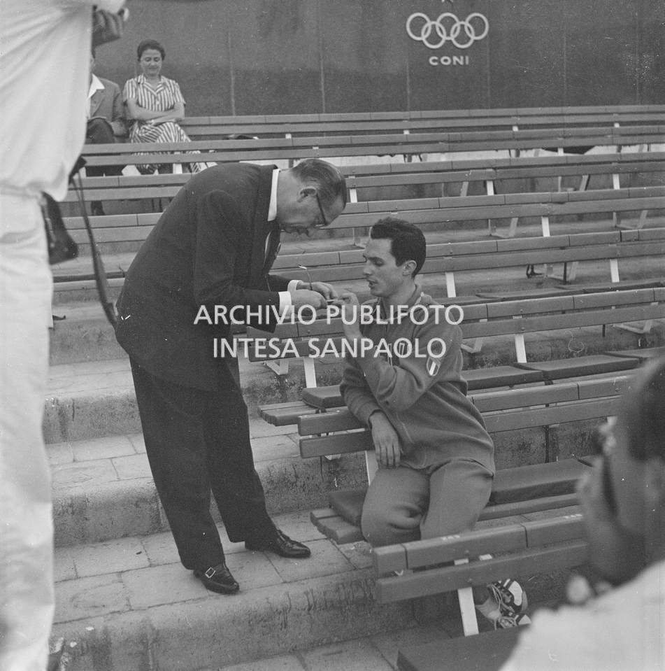 Un uomo osserva la medaglia d'oro, al collo di Livio Berruti, vinta nei 200 metri piani, XVII Olimpiade a Roma